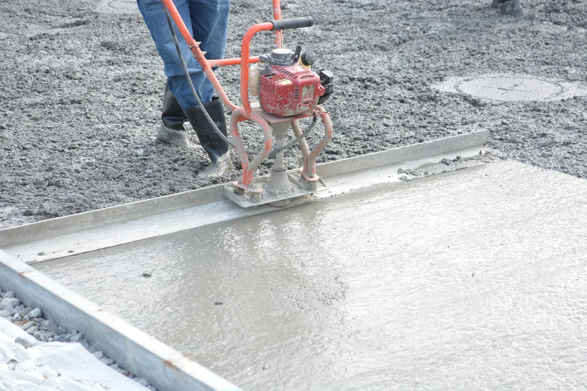 Concrete finisher smoothing a slab by hand with a trowel (stock placeholder photo)