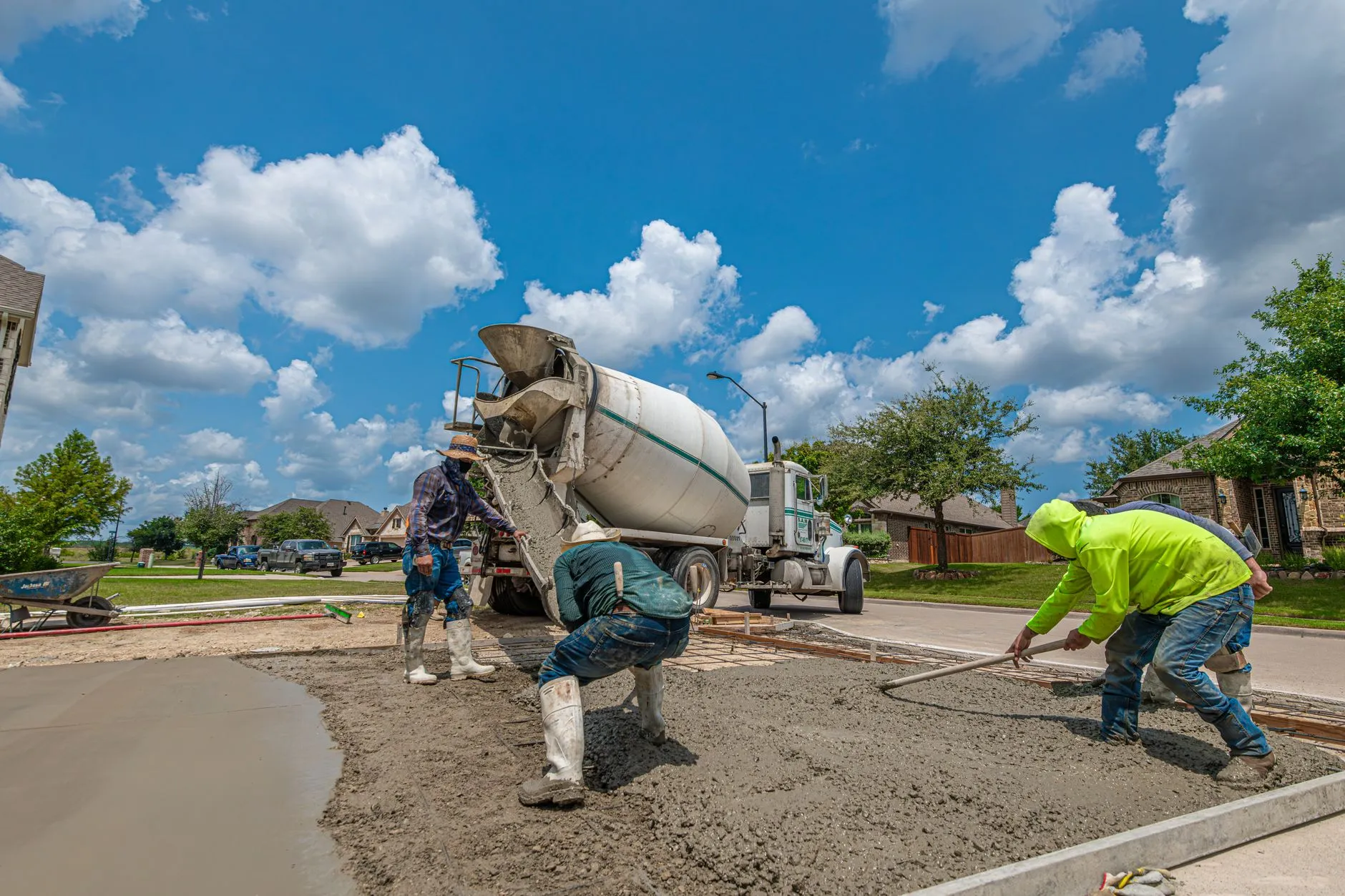 Crew placing and screeding fresh concrete on a residential driveway (stock placeholder photo)