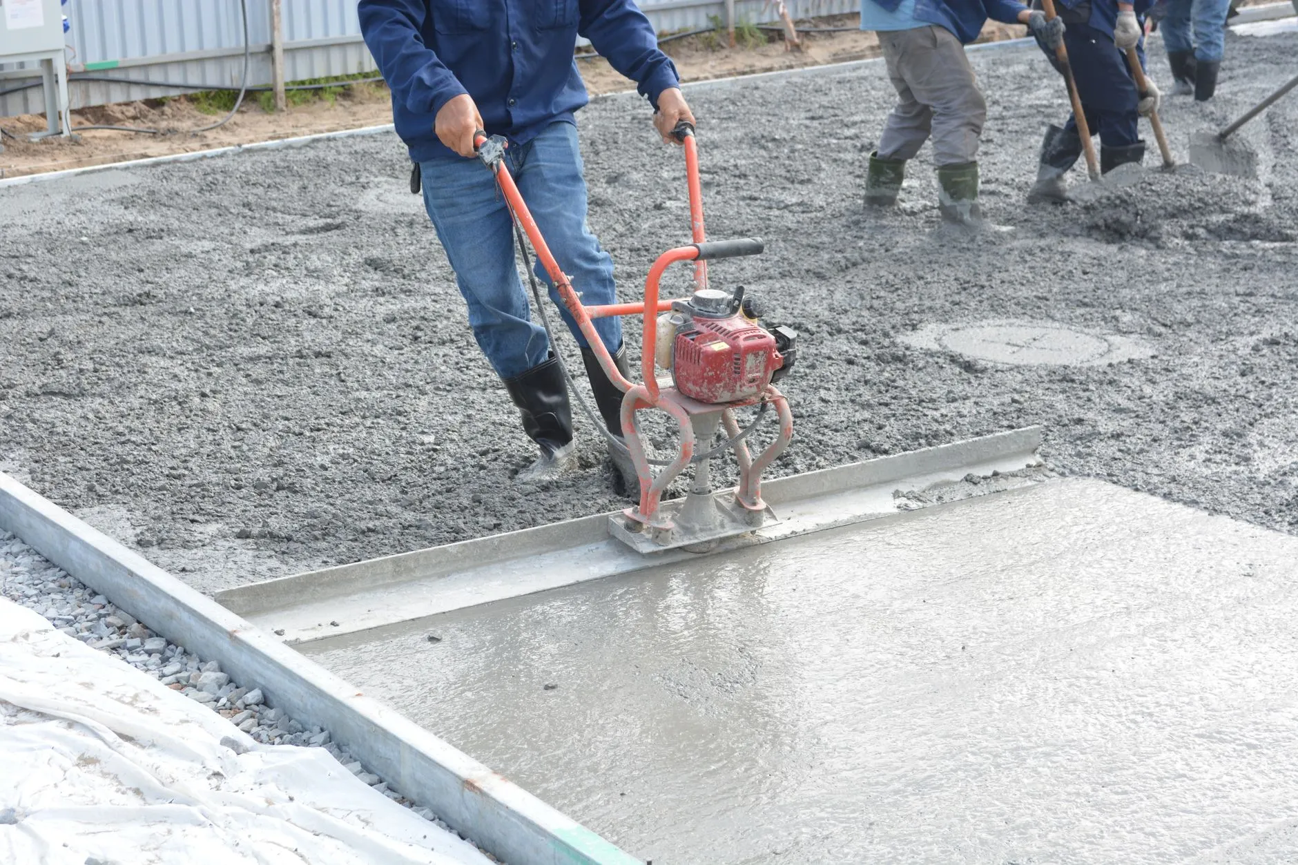 Worker finishing a fresh concrete slab (stock placeholder photo)